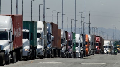 In this July 22, 2019 photo, trucks hauling shipping containers wait to unload at the Port of Oakland in Oakland, Calif.