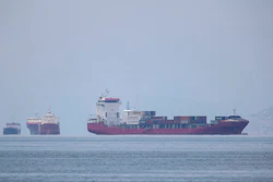 A cargo ship approaches the port of Piraeus as other ships are anchored.