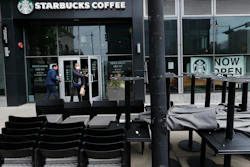 In this May 21 file photo, patrons to a Starbucks in the Chicago neighborhood of Hyde Park walk past stacked chairs and tables.