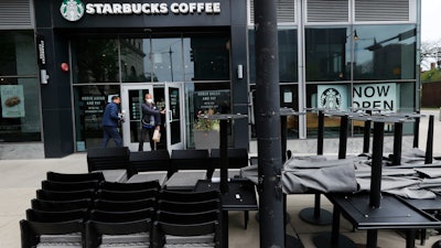 In this May 21 file photo, patrons to a Starbucks in the Chicago neighborhood of Hyde Park walk past stacked chairs and tables.