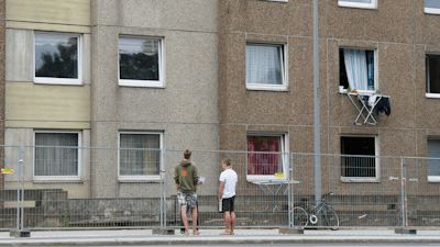 Two people stand at a fence separate a quarantined apartment building in Goettingen, Germany on Monday, June 22. The city council has quarantined an entire residential complex to contain the coronavirus in the area.