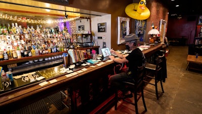 Michael Neff, co-owner of the Cottonmouth Club, works on a computer while sitting at the bar on June 23 in Houston. Neff closed his downtown bar because of concerns within the industry as the number COVID-19 case continues to rise in Houston.