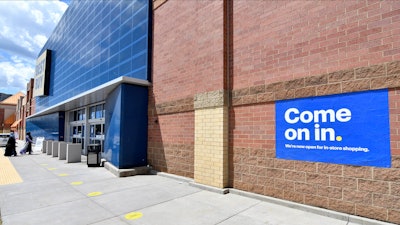 Shoppers, left, head to the entrance as a sign on the outside wall invites customers to shop inside a Best Buy store.