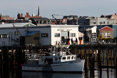 This March 25, 2020, file photo shows workers gathered outside the Portland Fish Exchange after unloading fish in Portland, Maine. On this day just one boat brought in a load of fish.