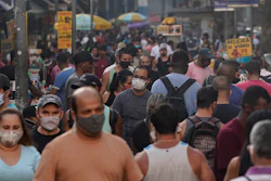 Pedestrians, some wearing protective face masks, walk through a street market in downtown Rio de Janeiro, Brazil on June 25.