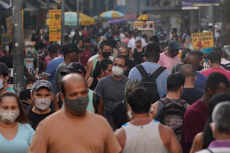 Pedestrians, some wearing protective face masks, walk through a street market in downtown Rio de Janeiro, Brazil on June 25.