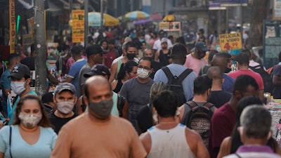 Pedestrians, some wearing protective face masks, walk through a street market in downtown Rio de Janeiro, Brazil on June 25.
