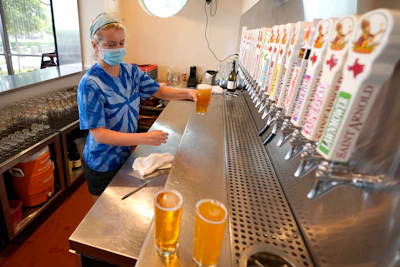 Bartender Katie McGranahan pours beers at the Saint Arnold Brewing Company onJune 26 in Houston. Texas Gov. Greg Abbott announced Friday that he is shutting bars back down and scaling back restaurant capacity to 50%, in response to the increasing number of COVID-19 cases in Texas.