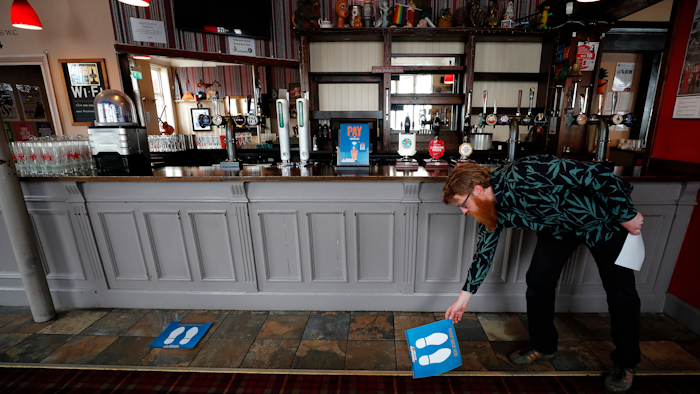 Owner Are Kjetil Kolltveit from Norway places markers for social distancing on the front of the bar at the Chandos Arms pub in London on Wednesday, July 1.