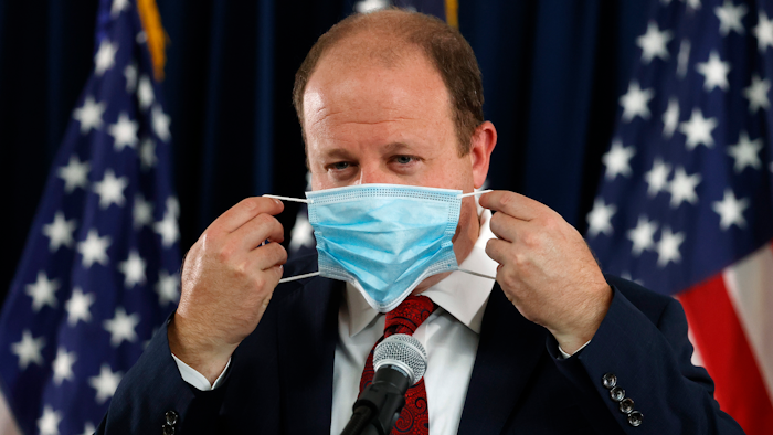 Colorado Governor Jared Polis puts on his face mask after concluding a news conference on the state's efforts against the new coronavirus on Tuesday, July 21 in Denver.