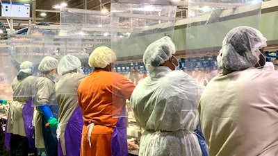 In this April photo, Tyson Foods workers wear protective masks and stand between plastic dividers at the company's Camilla, Georgia poultry processing plant.