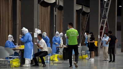 Workers in protective suits administer coronavirus tests at a COVID-19 testing site for those who were potentially exposed to the coronavirus at a wholesale food market in Beijing on Wednesday, June 17. As the number of cases of COVID-19 in Beijing climbed in recent days following an outbreak linked to a wholesale food market, officials announced they had identified hundreds of thousands of people who needed to be tested for the coronavirus.