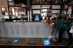 Owner Are Kjetil Kolltveit from Norway places markers for social distancing on the front of the bar at the Chandos Arms pub in London on Wednesday, July 1.