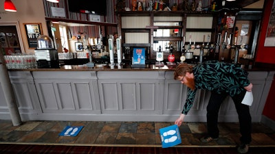Owner Are Kjetil Kolltveit from Norway places markers for social distancing on the front of the bar at the Chandos Arms pub in London on Wednesday, July 1.