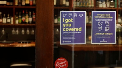 Signs advising social distancing and wearing face masks are posted on a door of The Barrel Room restaurant during the coronavirus outbreak in San Francisco on July 14. The Barrel Room, a San Francisco wine bar and restaurant, cautiously reopened last week, hoping to salvage as much of 2020 as possible from the coronavirus pandemic and the lockdowns meant to contain it.