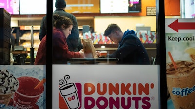 In this Jan. 30, 2019 file photo, customers sit inside a Dunkin' Donuts in New York.