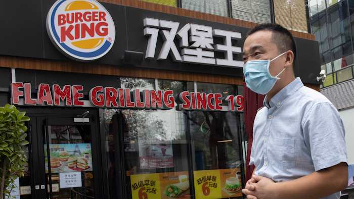 In this file photo taken July 17, 2020, a man wearing a mask to curb the spread of the coronavirus walks past a Burger King restaurant franchise in Beijing.