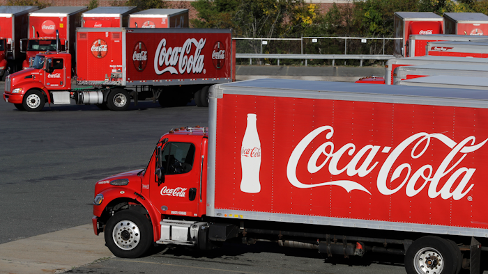In this Oct. 14, 2019 file photo, a truck with the Coca-Cola logo, behind left, maneuvers in a parking lot at a bottling plant in Needham, MA.