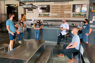 In a July 2020 photo provided by Wolf's Ridge Brewing, owner Bob Szuter, employees Allison Randolph and Alicia Herrmann, sous chef Andy Zamagias, general manager Corey Schlosser and employee Andy Powell, from left, gather inside the restaurant's tap room in Columbus, Ohio. Szuter says he’s trying to figure out new ways to bring in revenue, focusing more on the brewery side of the business until it’s safe to have a full dining room.