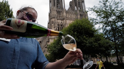 A waitress serves a glass of champagne at La Grande Georgette restaurant in front of the cathedral in Reims, the Champagne region, east of Paris, on July 28.