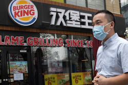 In this file photo taken July 17, 2020, a man wearing a mask to curb the spread of the coronavirus walks past a Burger King restaurant franchise in Beijing.