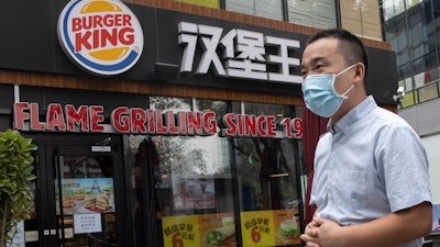 In this file photo taken July 17, 2020, a man wearing a mask to curb the spread of the coronavirus walks past a Burger King restaurant franchise in Beijing.