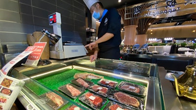 A worker weighs beef products on sale at a food court in Beijing on Friday, Aug. 28.