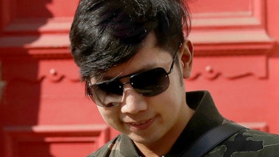 In this April 5, 2017, file photo, Vorayuth 'Boss' Yoovidhya, whose grandfather co-founded energy drink company Red Bull, walks to get in a car as he leaves a house in London. A Thai court on Tuesday, Aug. 25, 2020 issued a new arrest warrant for an heir to the Red Bull energy drink fortune, a month after news that prosecutors had dropped a long-standing charge against him caused widespread uproar and anger.