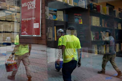 Workers are reflected in a window of a bookstore on Monday, Sept. 28 in the Harvard Square neighborhood of Cambridge, Mass.