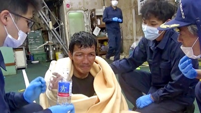 In this image made from video released by the 10th Regional Japan Coast Guard Headquarters, a rescued crew member of a Panamanian cargo ship takes a bottle of water as he speaks to Japanese Coast Guard members off the Amami Oshima, Japan Wednesday, Sept. 2, 2020. Japanese rescuers have safely plucked the crew member from the sea while searching for the cargo ship carrying more than 40 crew and thousands of cows went missing after sending a distress call off the southern Japanese island.