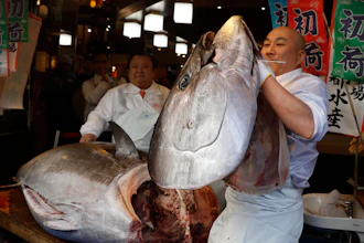 In this Jan. 5, 2020 photo, a sushi chef holds up the head of a bluefin tuna at a restaurant in Tsukji market area in Tokyo, after it was sold at the first auction of the year at Tokyo's Toyosu fish market.