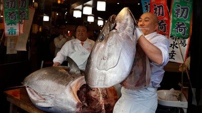 In this Jan. 5, 2020 photo, a sushi chef holds up the head of a bluefin tuna at a restaurant in Tsukji market area in Tokyo, after it was sold at the first auction of the year at Tokyo's Toyosu fish market.