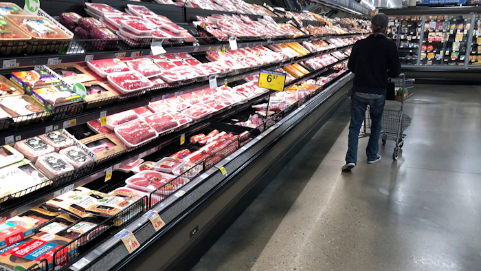 In this May 10, 2020 photo, a shopper pushes his cart past a display of packaged meat in a grocery store in southeast Denver.