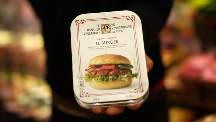 A store clerk shows a plant-based burger at a supermarket chain in Brussels on Friday, Oct. 23.