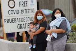 Two women and a child wait to take a coronavirus test at a mobile testing site.