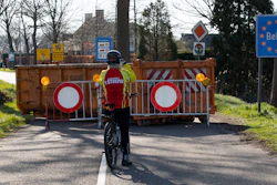 In this March 23, 2020 photo, a cyclist takes images of a barricaded backroad used by locals on the Netherlands border with Belgium between Chaam, southern Netherlands, and Meerle, Northern Belgium.