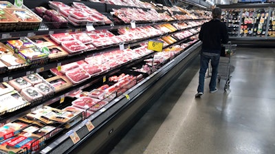 In this May 10, 2020 photo, a shopper pushes his cart past a display of packaged meat in a grocery store in southeast Denver.