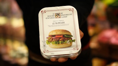 A store clerk shows a plant-based burger at a supermarket chain in Brussels on Friday, Oct. 23.