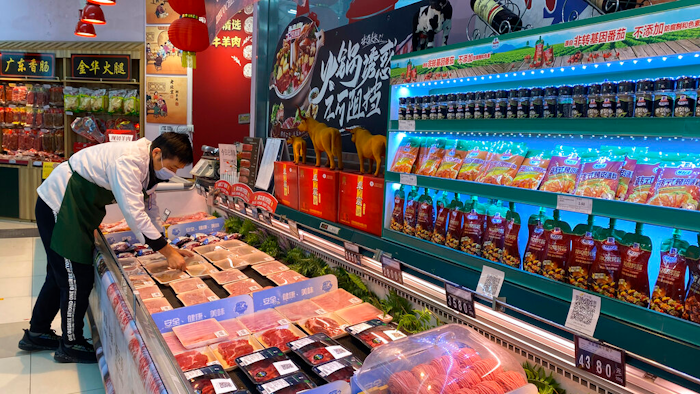 A worker wearing a mask handles meat products including beef from New Zealand packaged with a QR-code linked to its COVID test results at a supermarket in Beijing, Tuesday, Nov. 24, 2020.