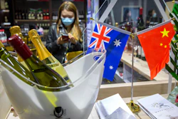 A staff member wearing a face mask stands near a display of Australian wines at the China International Import Expo in Shanghai on Nov. 5.