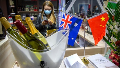 A staff member wearing a face mask stands near a display of Australian wines at the China International Import Expo in Shanghai on Nov. 5.