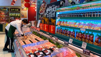 A worker wearing a mask handles meat products including beef from New Zealand packaged with a QR-code linked to its COVID test results at a supermarket in Beijing, Tuesday, Nov. 24, 2020.