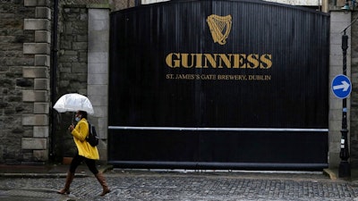 A woman passes the Guinness brewery in Dublin's city centre Wednesday Nov. 11, 2020. Irish brewer Guinness announced Wednesday it is recalling cans of its recently launched non-alcoholic stout in Britain, as a precautionary measure over contamination concerns.