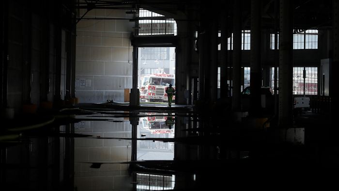 In this May 23, 2020 photo, a fire official is shown reflected in a puddle in a warehouse after a fire broke out before dawn on a pier at Fisherman's Wharf in San Francisco.
