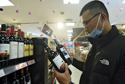 A man wearing a face mask compares two bottles of Australian wine at a supermarket in Hangzhou in east China's Zhejiang province on Nov. 27.