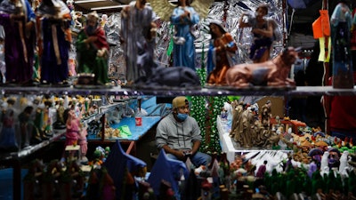 A vendor sells nativity figurines, in a Christmas market where organizers were still deciding if they would close at 5 p.m., in accordance with a new state mandate intended to help slow the spread of COVID-19, in Ecatepec, Mexico State, on the outskirts of Mexico City on Dec. 14.
