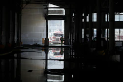 In this May 23, 2020 photo, a fire official is shown reflected in a puddle in a warehouse after a fire broke out before dawn on a pier at Fisherman's Wharf in San Francisco.