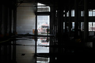 In this May 23, 2020 photo, a fire official is shown reflected in a puddle in a warehouse after a fire broke out before dawn on a pier at Fisherman's Wharf in San Francisco.