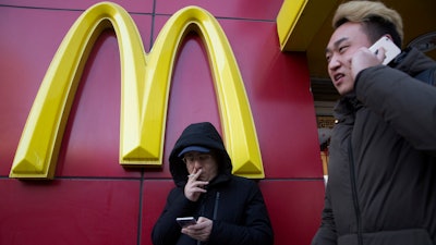 In this Jan. 10, 2017 file photo, a man smokes outside a McDonald's restaurant in Beijing, China.