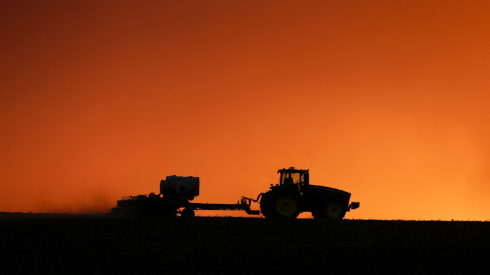 In this April 20, 2020, file photo, a farmer is silhouetted by the setting sun as a field is planted near Walford, IA.